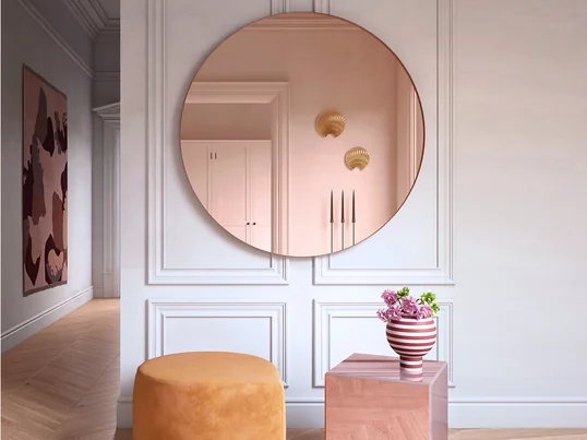 Circum-vægspejlet fra AYTM i stemningsudsigten: Det elegante spejl harmonerer perfekt med Varia Sculptural Vase og udvider optisk gangen.