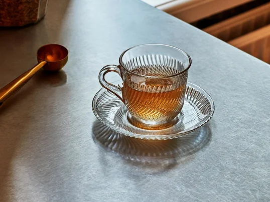 Den klassiske Pirouette-kop med matchende tallerken fra HAY overbeviser gennem det gennemsigtige materiale og det omgivende hvirvlende ribmønster.