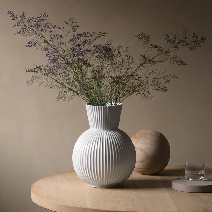 Lyngby Tura vase, H 34 cm, hvid af Lyngby Porcelæn ved siden af andre dekorative genstande på et sidebord