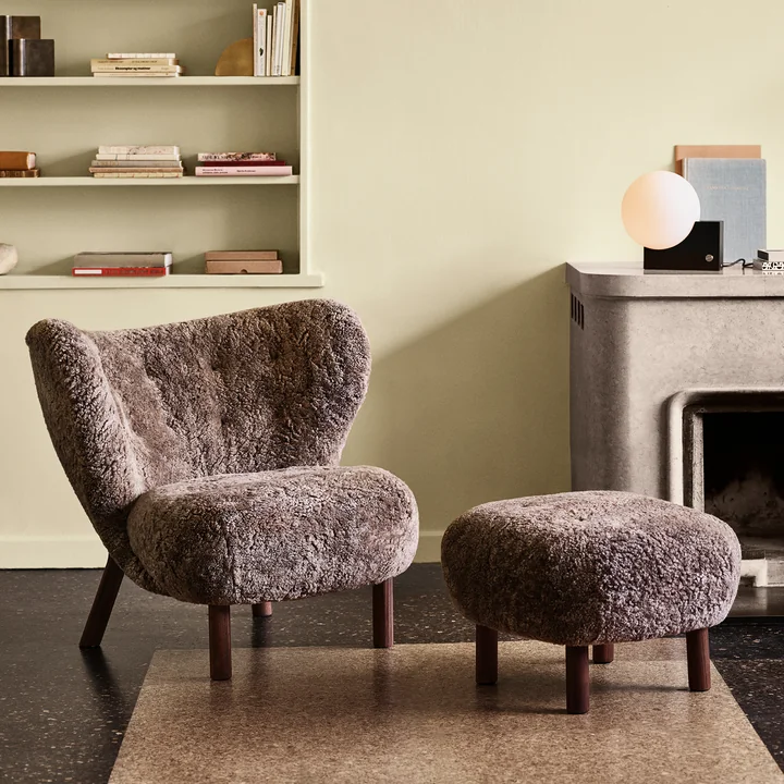 Den Little Petra Lounge Chair med puf fra & Tradition foran stenpejsen i opholdsstuen