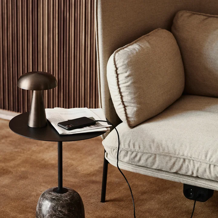 Como SC53 batteridrevet lampe fra & Tradition på et sort sidebord ved siden af en let sofa