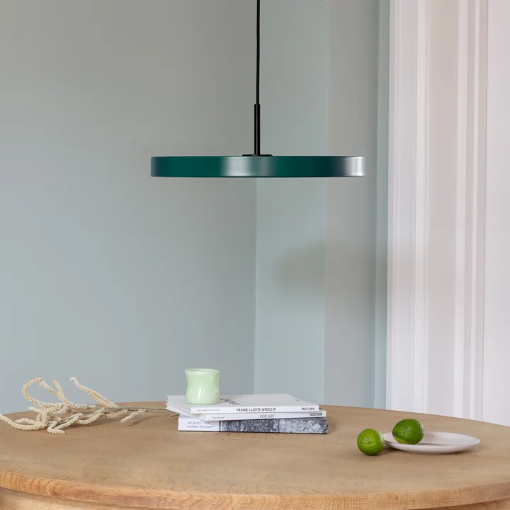 Asteria LED pendlen fra Umage i sort / forest green over et let, rundt spisebord i træ