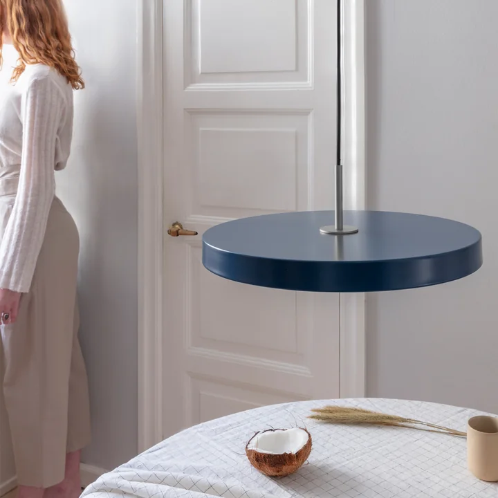 Asteria LED pendlen fra Umage i stål/benzin over et rundt spisebord med ternet loft