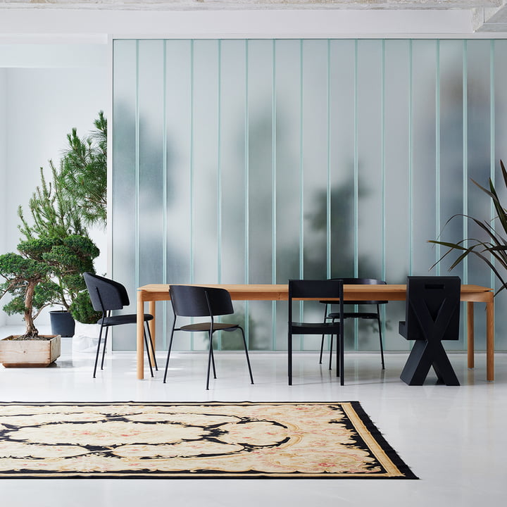 Wagner Dining Chair fra OUT Objekte unserer Tage i antracit på et stort spisebord i træ ved siden af andre mørke stole