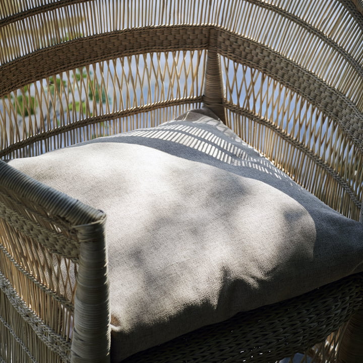 The Fine Outdoor Cushion fra House Doctor i en vævet udendørs lænestol