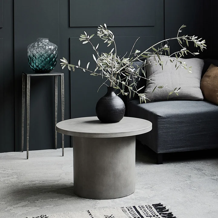Den Stone Beton sidebord af House Doctor foran en grå sofa i stuen