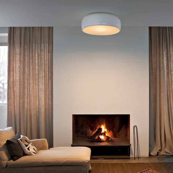 Smithfield Pro loftlampen fra Flos i stuen over en beige sofa med pejs